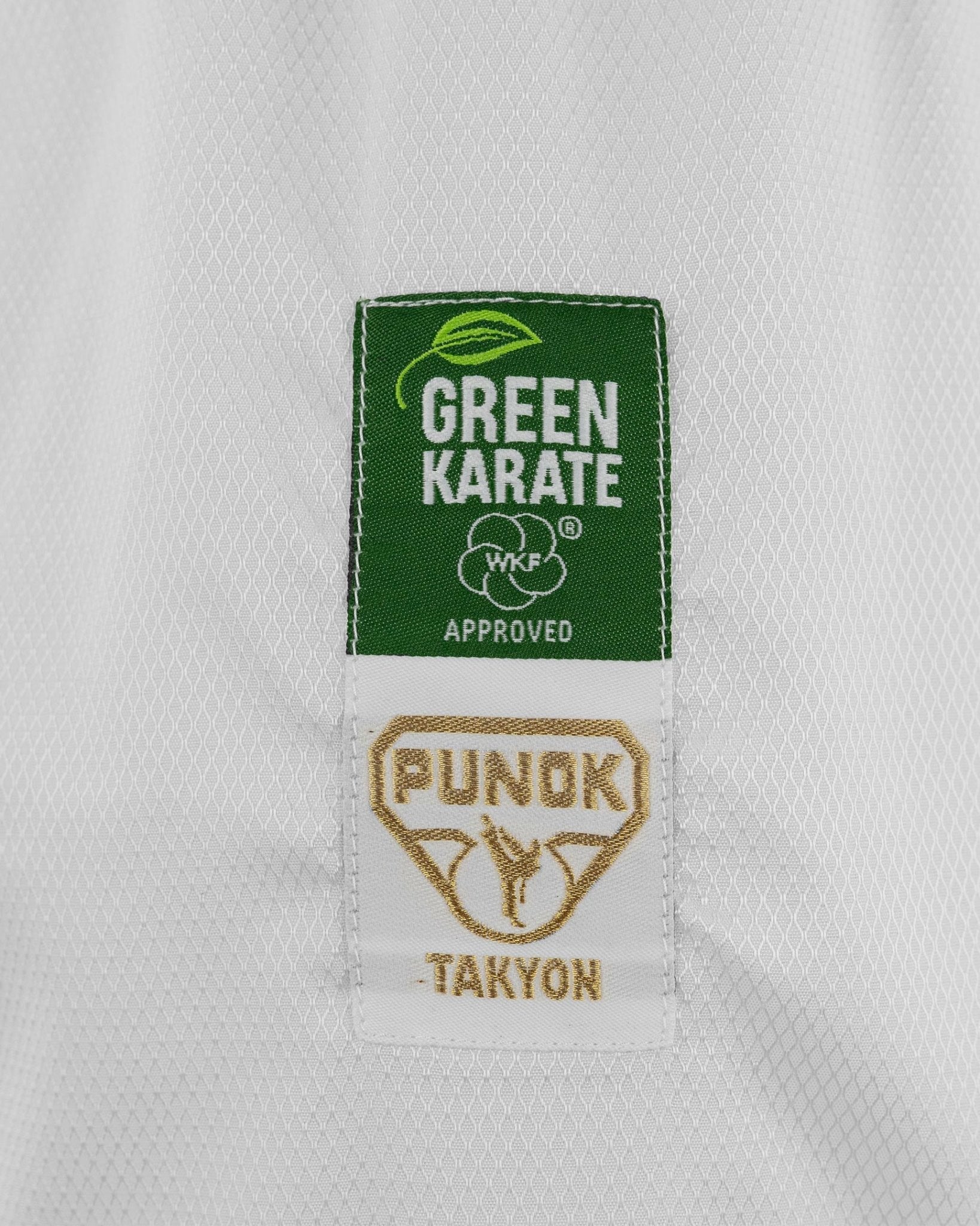 Close-up of Green Karate WKF approved and Punok TAKYON patches on white fabric