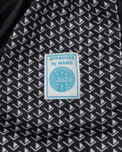 Tenacity pants fabric in dark with white geometric pattern and WAKO approval patch
