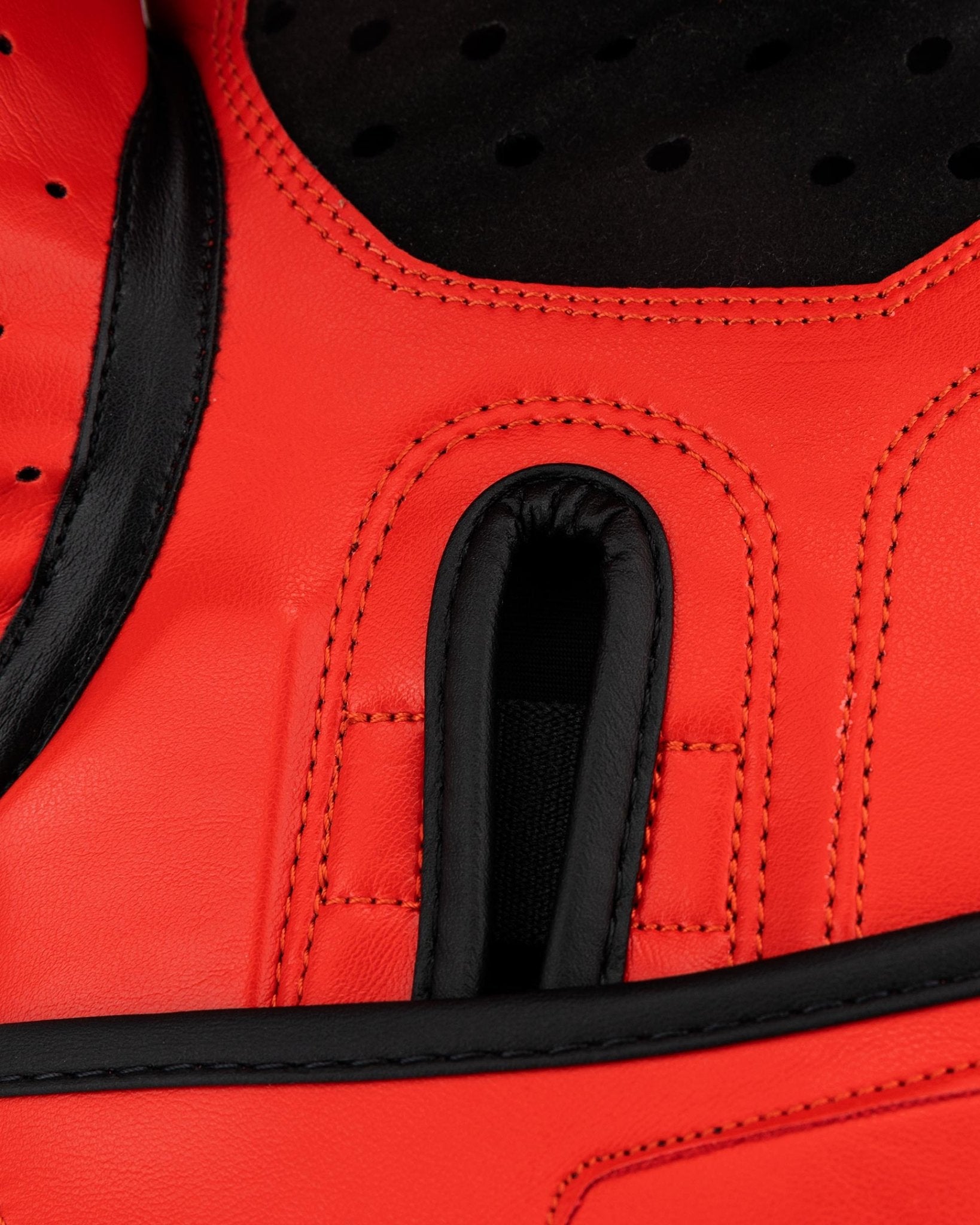 Close-up of red kickboxing glove palm padding with black ventilation insert and stitching