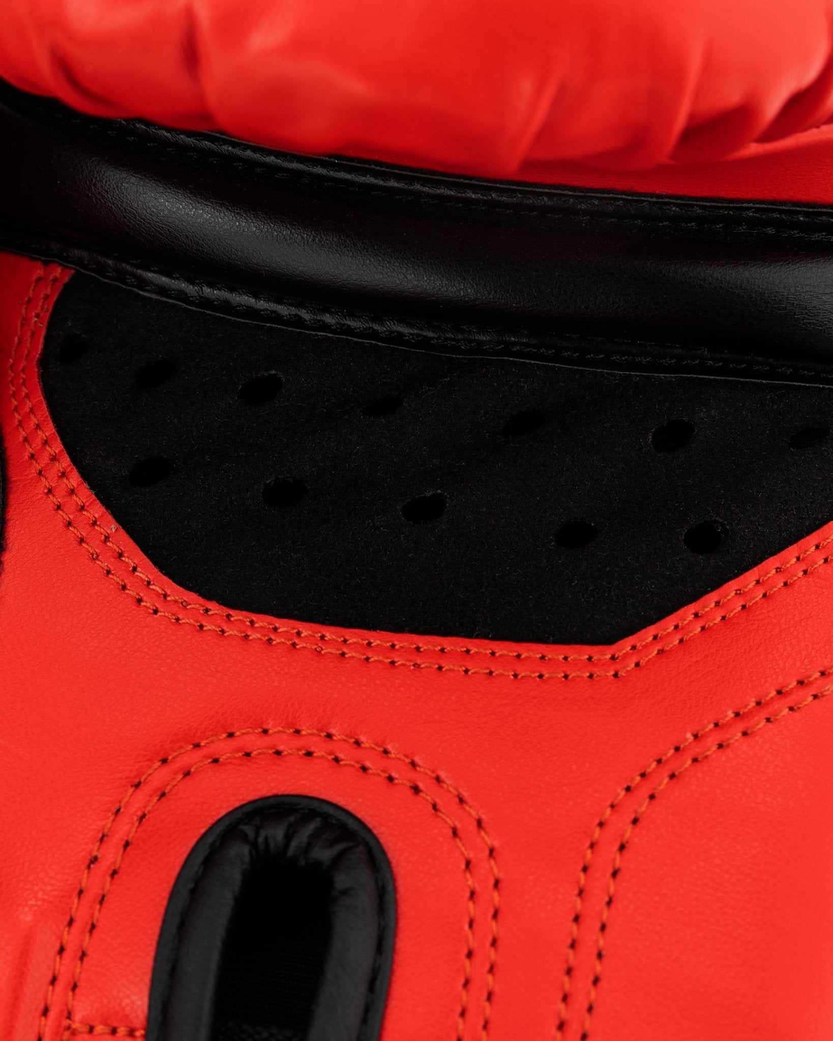 Close-up of red kickboxing glove interior, black ventilation panel and stitched edge