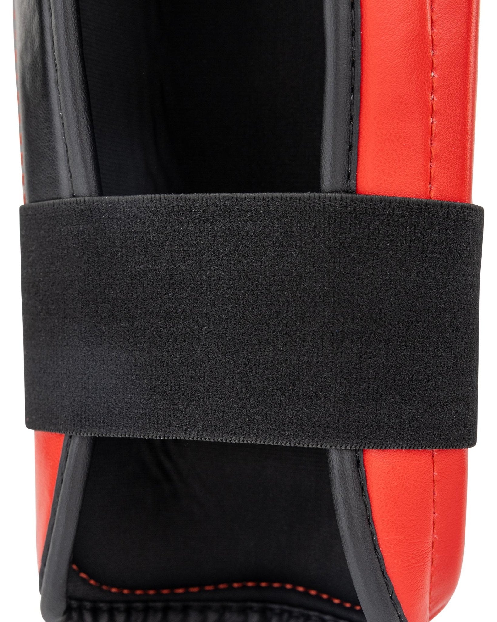 WAKO Drive shin guards close-up with black strap over red-and-black padded shell.