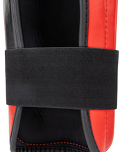 WAKO Drive shin guards close-up with black strap over red-and-black padded shell.
