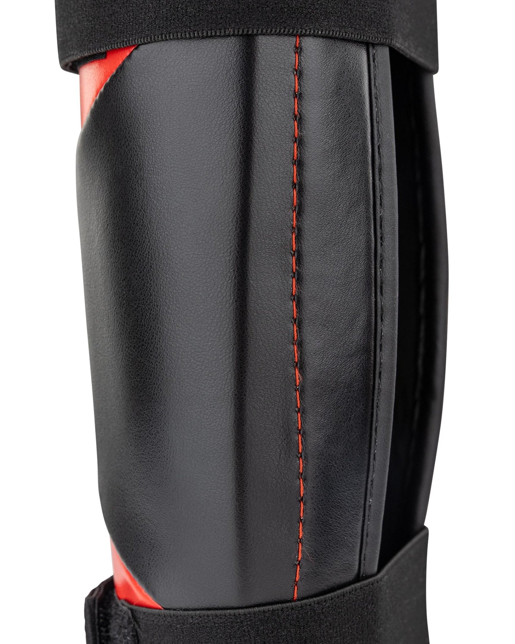 WAKO Drive shin guards close-up with black shell, red stitching, and textured surface.