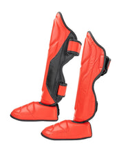 Orange shin instep guards with black side straps and curved padded front.