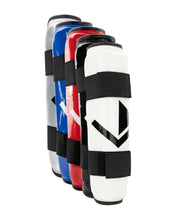 Multiple shin guards shown together in red, blue, white, and silver with black straps