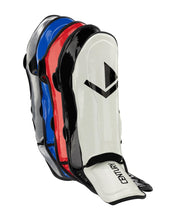Pair of shin guards in white, black, blue, and red with black straps and V-logo